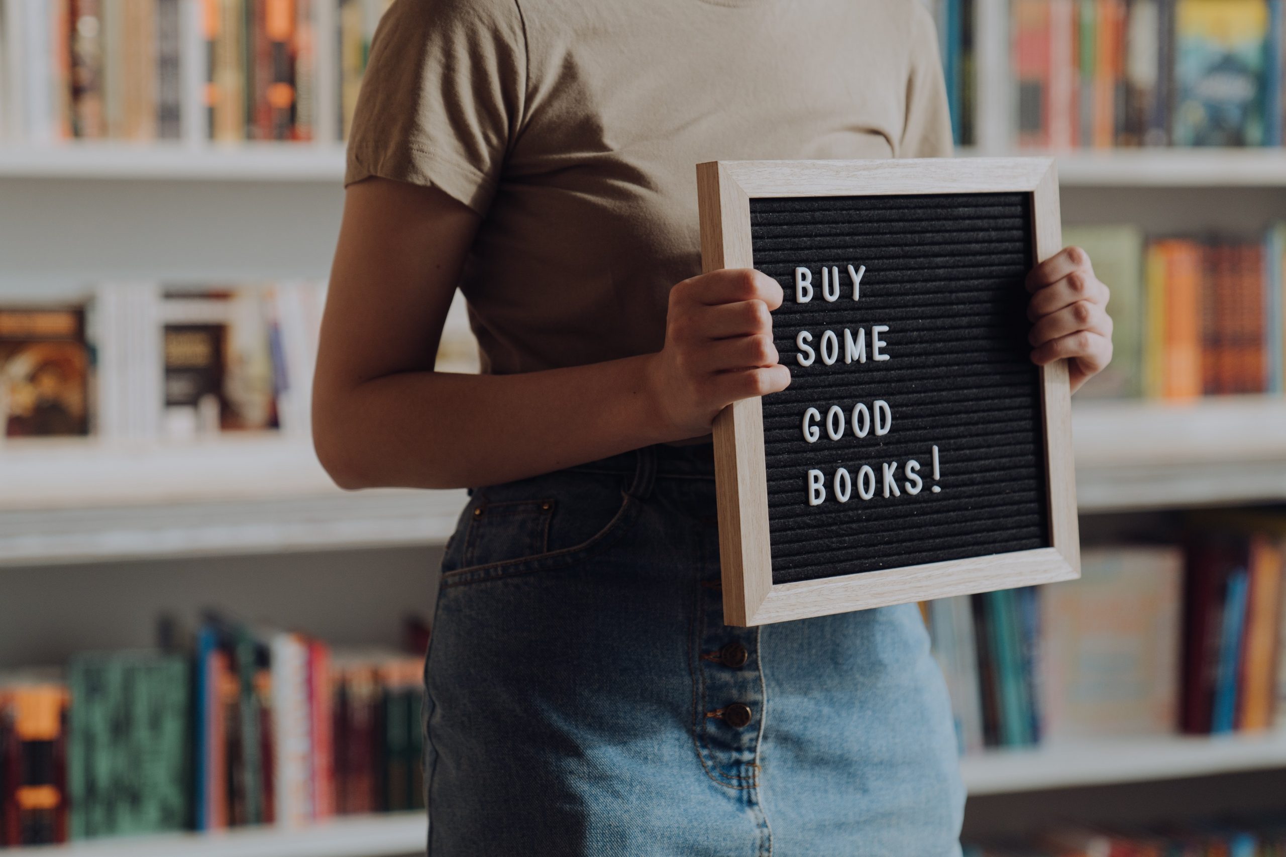 Woman holding "Buy Some Good Books" sign.